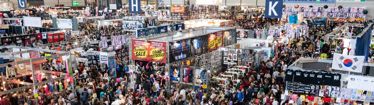 Aufnahme einer Messehalle der Manga-Comic-Con. Es sind viele Stände und Menschen zu sehen. Aufnahme einer Messehalle der Manga-Comic-Con. Es sind viele Stände und Menschen zu sehen.