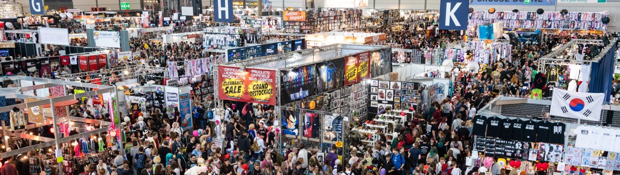 Aufnahme einer Messehalle der Manga-Comic-Con. Es sind viele Stände und Menschen zu sehen.