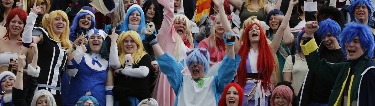 Large group photo of cosplayers, all laughing joyfully and some raising their arms.
