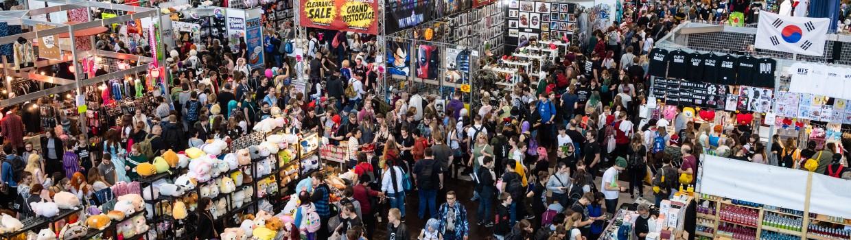 Aufnahme einer Messehalle der Manga-Comic-Con. Es sind viele Stände und Menschen zu sehen.
