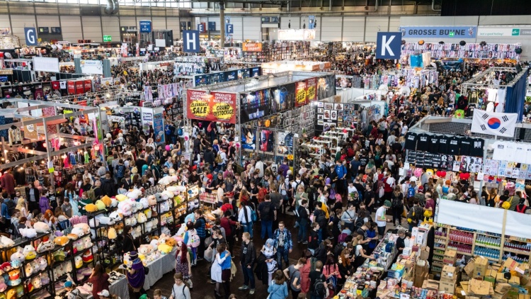 Aufnahme einer Messehalle der Manga-Comic-Con. Es sind viele Stände und Menschen zu sehen.