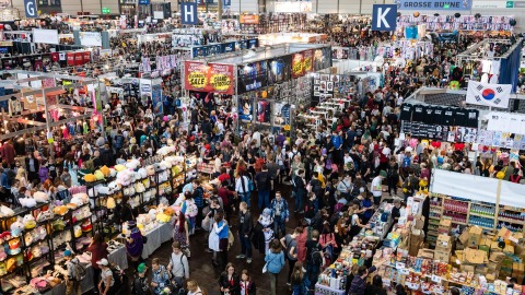 Shot of a convention hall at the Manga-Comic-Con, showing many booths and people.
