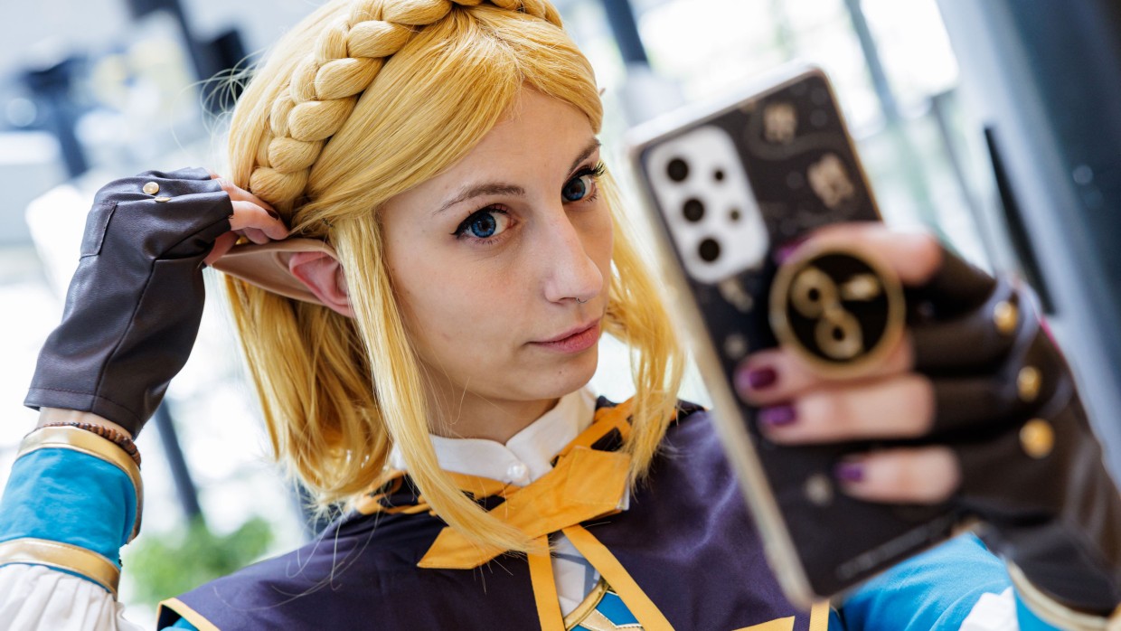 Ein:e Zelda-Cosplayer:in auf der Manga-Comic-Con 2023 prüft ihren Look in ihrer Handykamera