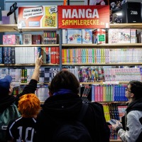 Besucher:innen an einem Messestand mit Mangaheften auf der Manga-Comic-Con 2024