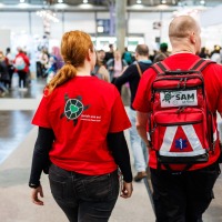 2 Personen vom Awareness Team SAM der Manga Comic Con 2025 laufen durch die Messehalle