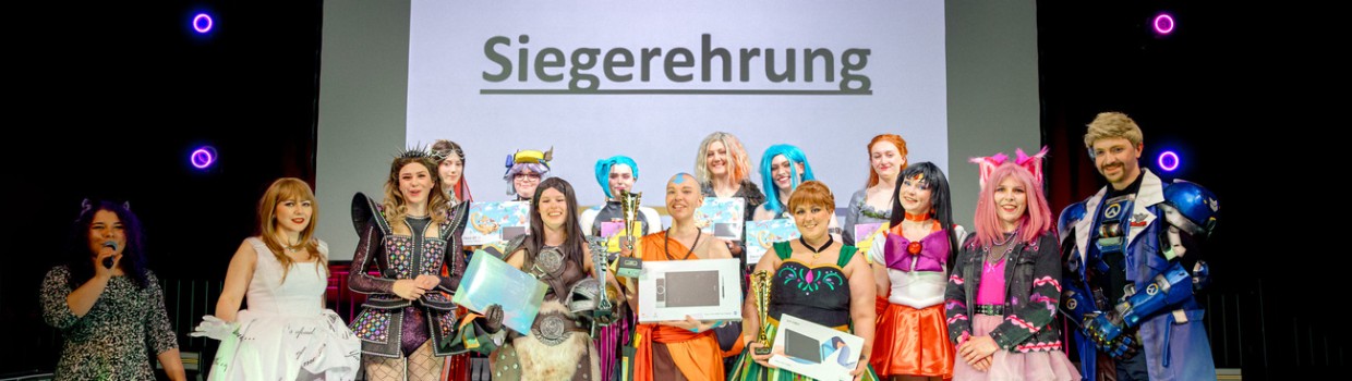 Gruppenfoto mit allen Teilnehmer:innen und Jury der Cosplay Meisterschaft Deutschland 2025 auf der Großen Bühne der Manga Comic Con
