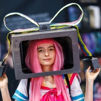 Cosplayer:in mit pinker Perücke und Schleifen-Box auf dem Kopf auf der Manga Comic Con 2025