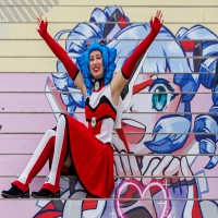 Macoco, the mascot of the Manga Comic Con 2025, is sitting on a staircase
