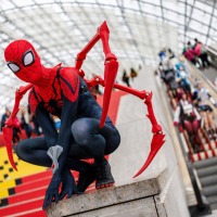 Person in a Spider-Man costume posing in front of the red staircase in the entrance area of the Glass Hall at the Leipzig Trade Fair during the Manga Comic Con 2025