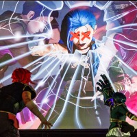 Zwei Cosplayer:innen vor einer großen Leinwand mit einem Manga-Charakter auf der Manga Comic Con 2025