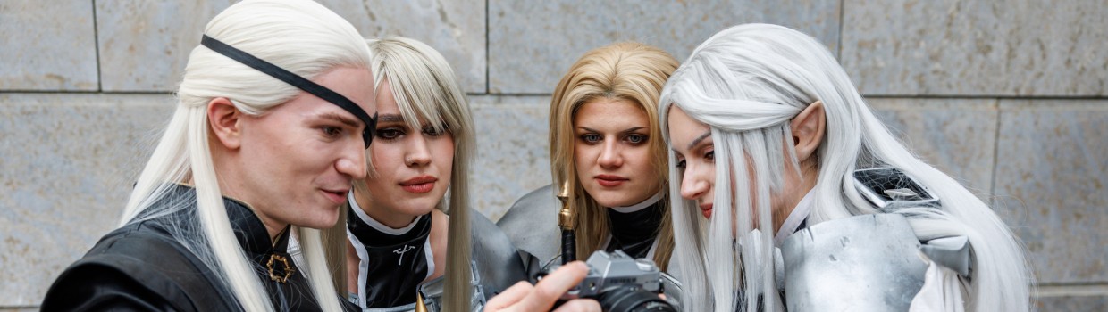 Vier Cosplayer:innen mit langen weißen Perücken schauen gemeinsam auf eine Kamera bei der Manga Comic Con 2025
