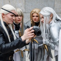Four cosplayers wearing long white wigs and look together at a camera at Manga Comic Con 2025.