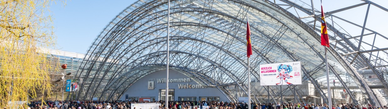 Außenansicht der Glashalle der Leipziger Messe mit vielen Besucher:innen davor zur Zeit der Manga Comic Con 2025
