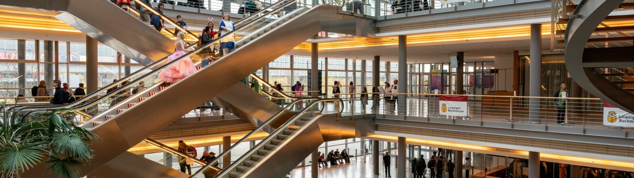 Das Atrium des Congress Center Leipzig mit vielen Besucher:innen auf Rolltreppen und Gängen