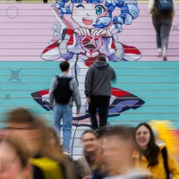 Visitors walk up a colorful staircase with a large manga motif at the Leipzig Exhibition Center during the Manga Comic Con 2025
