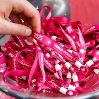 Close-up of a hand taking a pink admission wristband for Manga Comic Con 2025 from a bowl