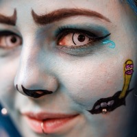 Close-up at Manga Comic Con of a face painted blue looking into the camera