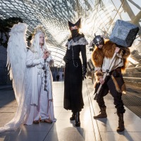 Three people in costume at Manga-Comic-Con 2025 pose in the glass hall of the Leipzig Trade Fair.