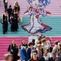 Besucher:innen der Manga Comic Con 2025 vor und auf einer Treppe auf der das Leipziger Messe Maskottchen abgebildet ist