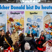 Besucher:innen vor vier großen Donald-Duck-Postern mit den Titeln 'Entdecker', 'Cosplayer', 'Sportler' und 'Romantiker' auf der Manga Comic Con 2025