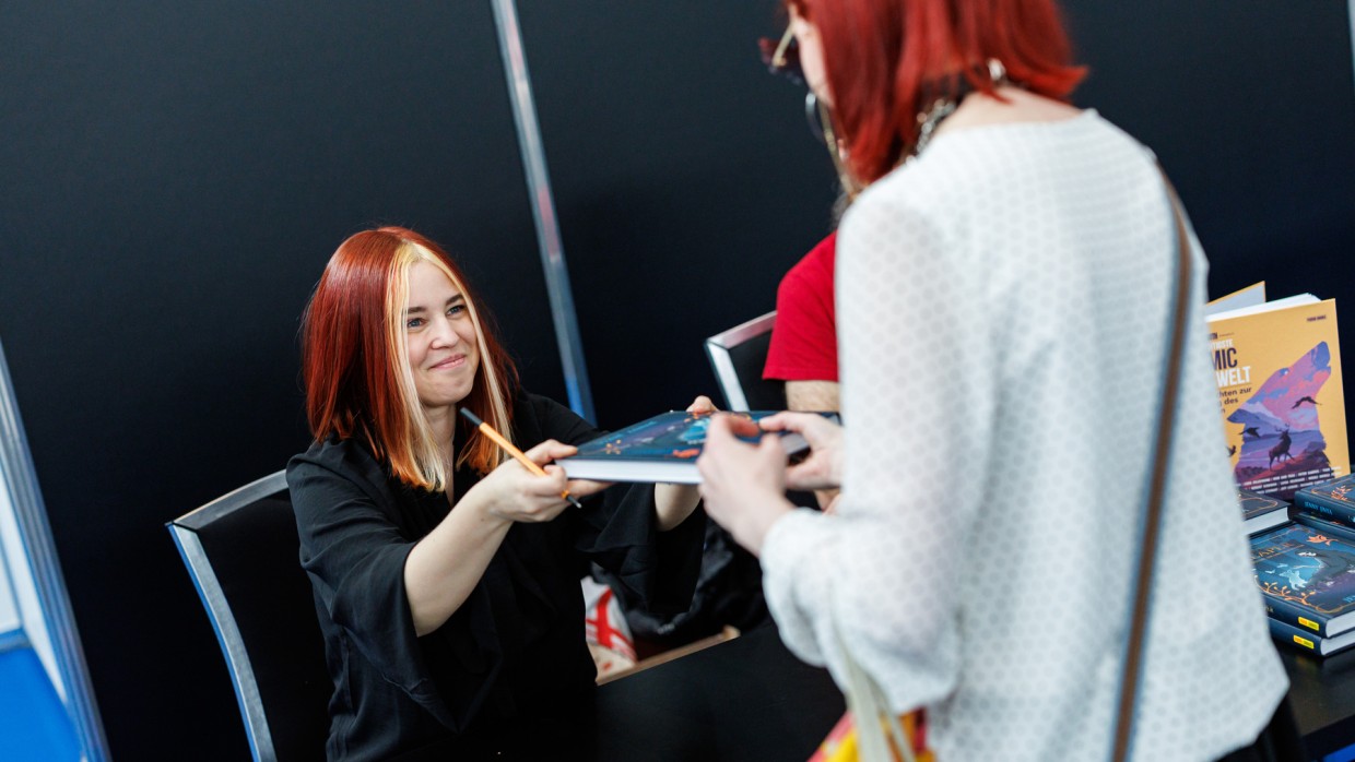 Jenny Jinya überreicht einem Fan ein signiertes Buch auf der Manga-Comic-Con 2025