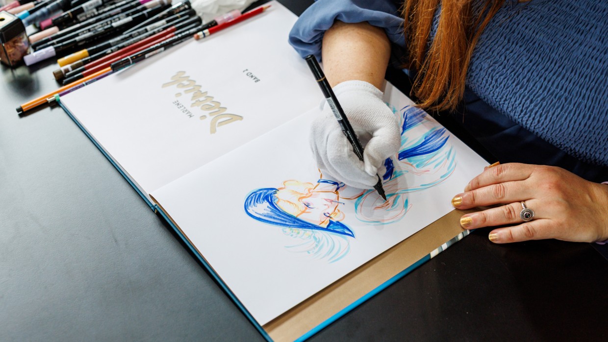 Künstlerin zeichnet in ein Buch mit Zeichnung auf der Manga-Comic-Con 2025