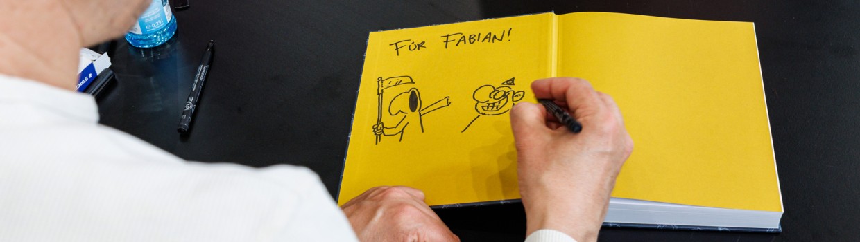 Ralph Rute signiert ein Buch mit Zeichnung auf der Manga-Comic-Con 2025